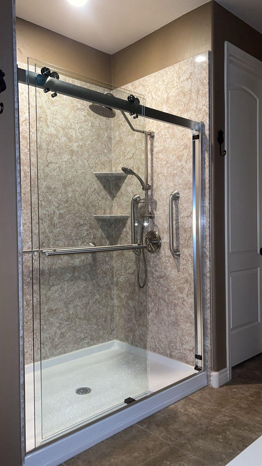 Finished shower with sliding glass door, rain head, handheld and a grab bar.