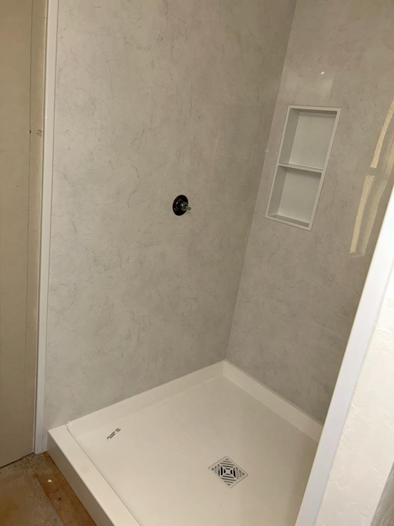 Shower base set and drained, with the recessed niche framed into the wall.