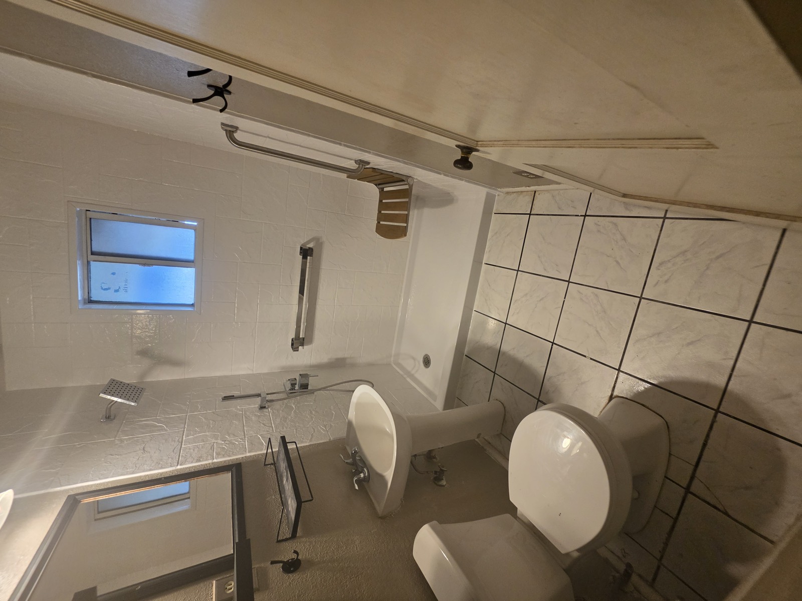 Low-threshold shower with a horizontal grab bar, a vertical entry bar, a fold-down seat and a handheld on a slide bar.