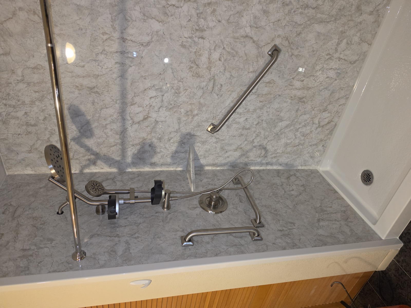 Shower interior showing an angled transfer bar, a horizontal bar and a handheld on a slide bar.
