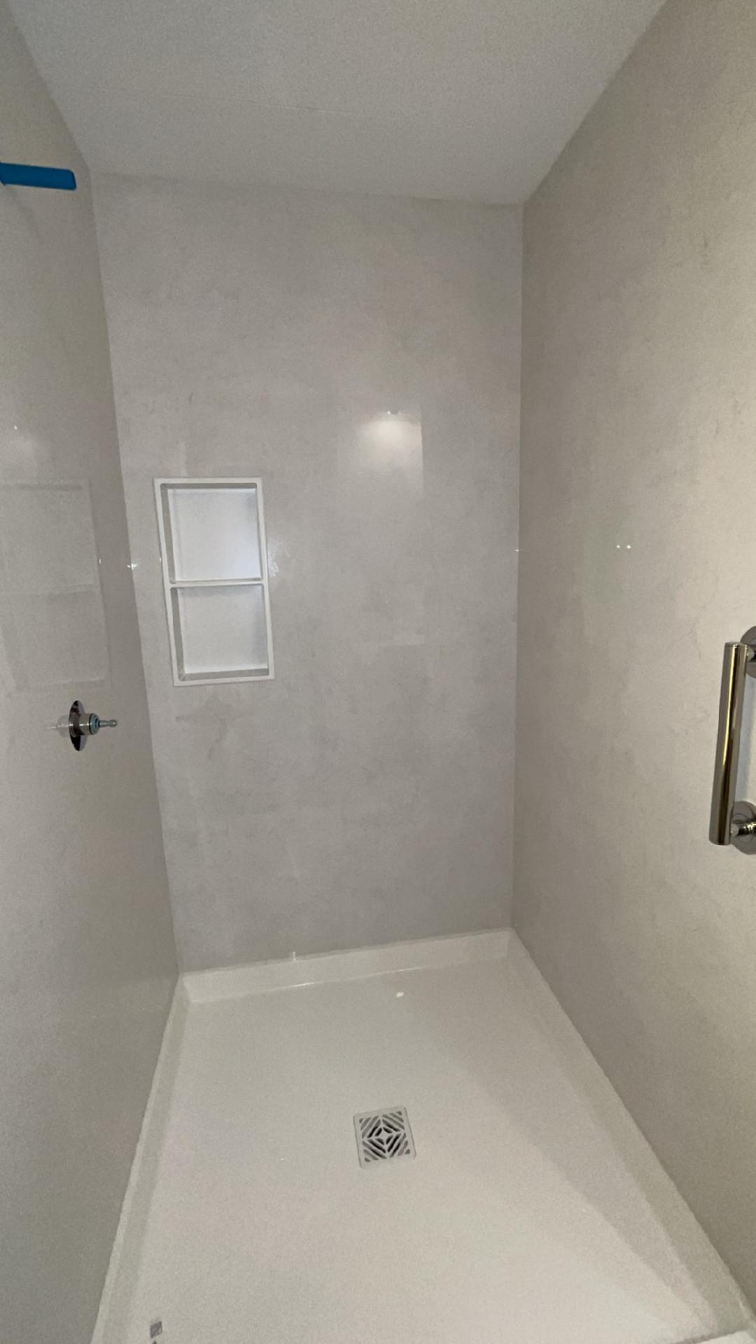 Shower walls installed with the niche finished and the valve rough-in visible.