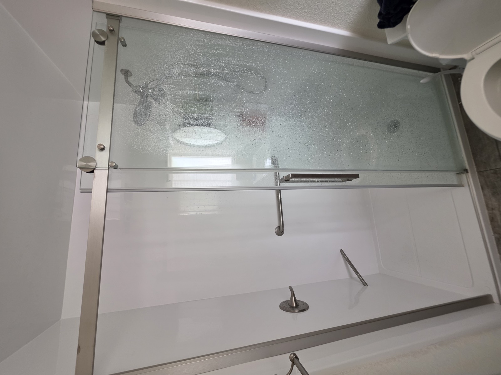 Finished walk-in shower with white surround and clear bypass glass doors.